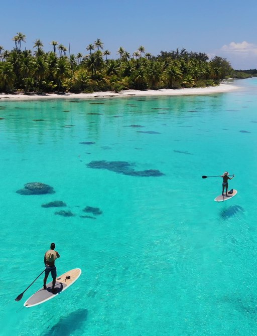 Two people on paddle boards in turquoise waters in French Polynesia