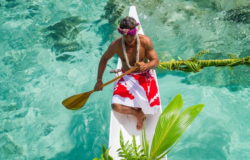 local man delivering food on Tahitian boat covered in beautiful flowers